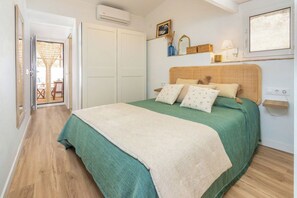 A bedroom with a bed, a green bedspread, a white blanket, and a wooden floor. - Casa con encanto a pie de playa (Tamariu)