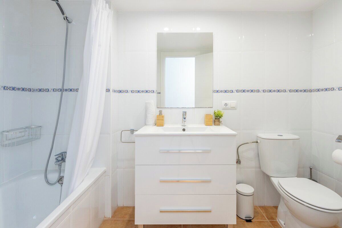 Une salle de bain moderne équipée d’une douche, de toilettes et d’un meuble-lavabo avec des tiroirs et un miroir.