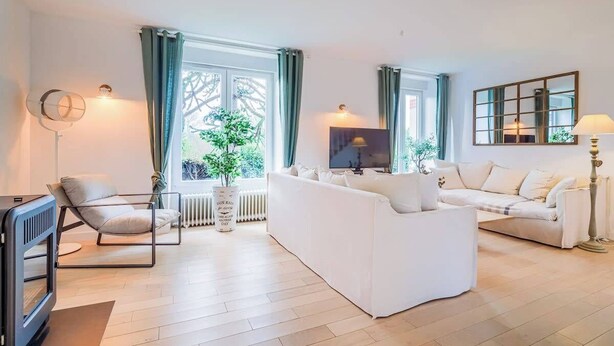 Una sala de estar moderna con un sofá, una silla, un televisor y una lámpara de pie.