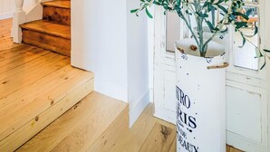 Una escalera de madera con barandillas blancas que conduce a una puerta con una planta en una maceta blanca.
