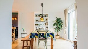 Un comedor con una mesa dispuesta para cuatro personas, una estantería y un ventanal grande.