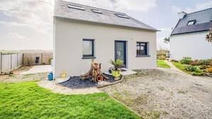Una moderna casa a due piani con tetto piatto, un piccolo giardino antistante e un vialetto sterrato.