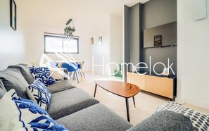 A modern living room with a sofa, coffee table, and a dining area with chairs and a table. - Maison au calme - plages à quelques minutes (Guidel)