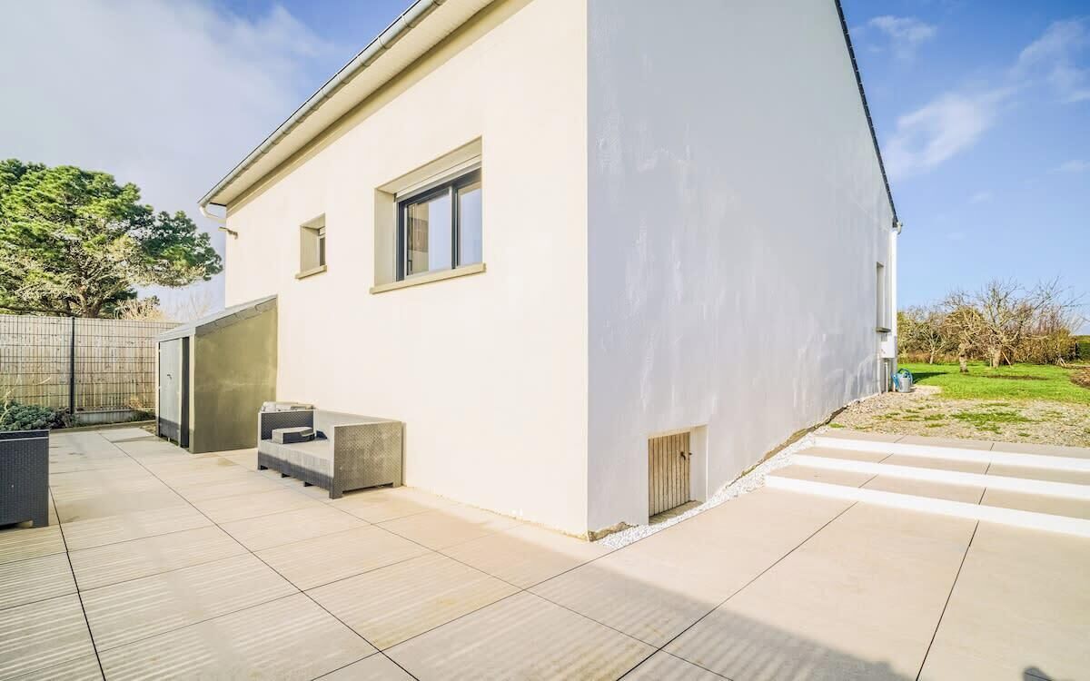 A modern house with a flat roof, a large window, and a concrete bench.