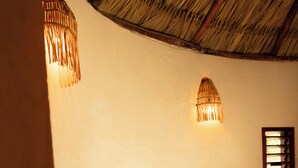 Una habitació amb sostre corbat, una taula de fusta, dues cadires i una làmpada penjada a la paret.