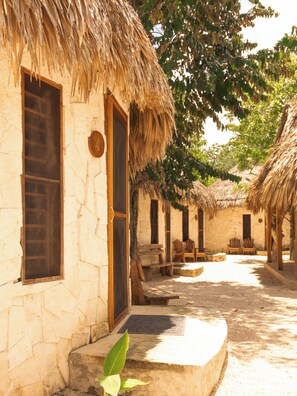 A row of thatched-roof cottages with stone walls, wooden doors, and benches.