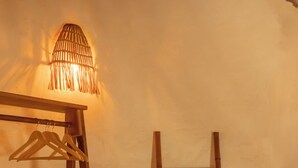 Una habitació amb un llit de fusta, una làmpada penjant, una escala de fusta i una catifa teixida.