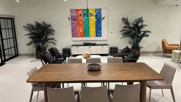 A modern dining area with a wooden table, white chairs, a buffet cabinet, and two potted plants.