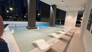 A modern indoor pool area with a view of the city at night.