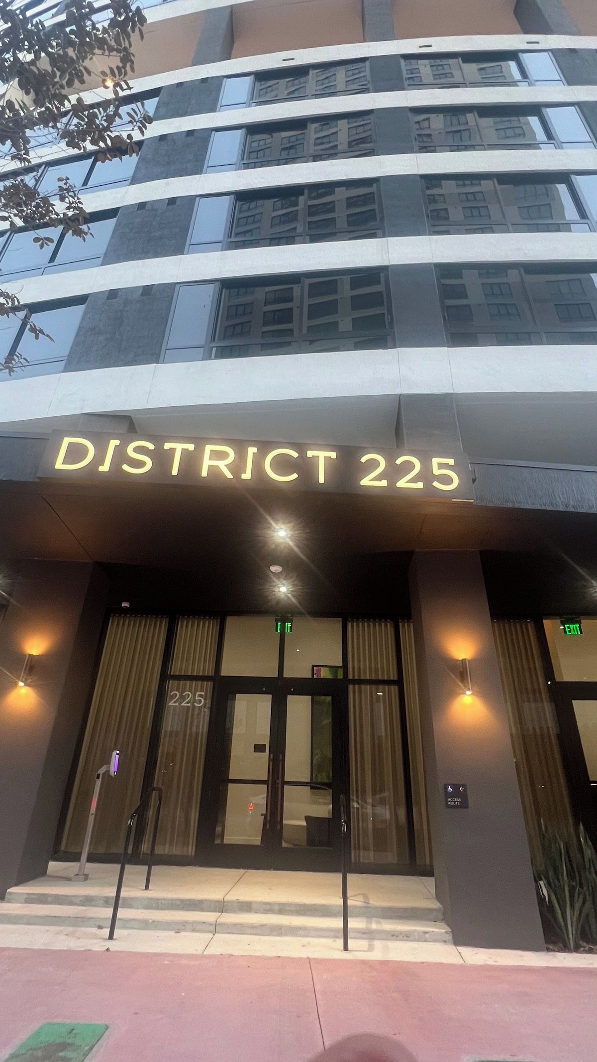 A hotel entrance with a sign reading 'DISTRICT 225' and an 'EXIT' sign above the door.