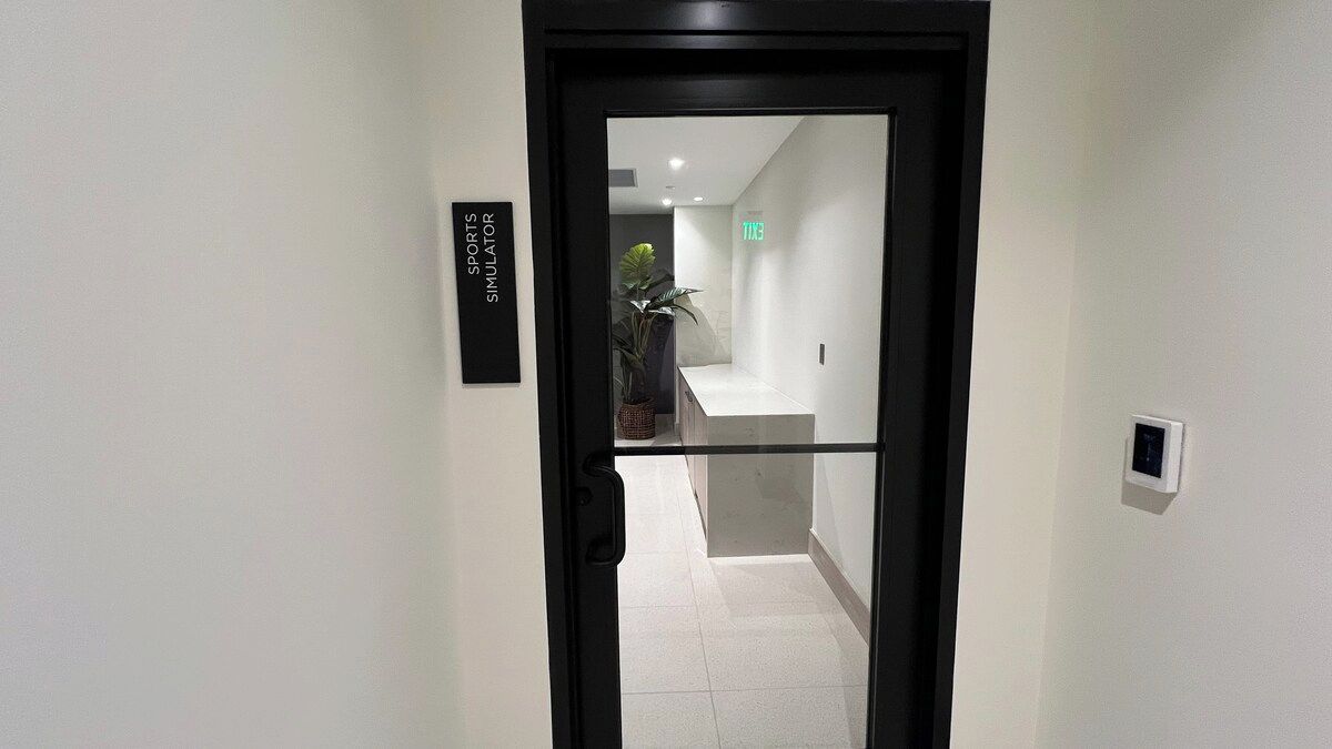A hallway with a door labeled 'SPORTS SIMULATOR' and a TGI emergency exit sign.