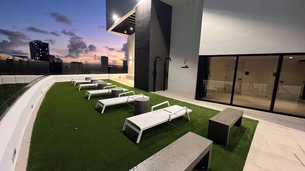Un área de lounge en la azotea con sillones blancos y una pequeña piscina.