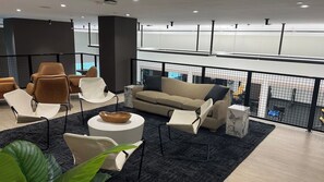 Un área de descanso moderna con disposición de asientos, una mesita de centro y vista a la piscina.