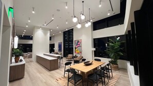 Une cuisine moderne avec un îlot en bois, des chaises noires et une table à manger.