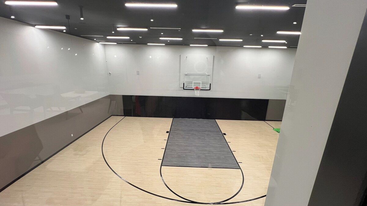 A basketball court with a wooden floor and a black mat in the center.