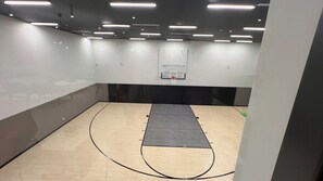 A basketball court with a wooden floor and a black mat in the center.