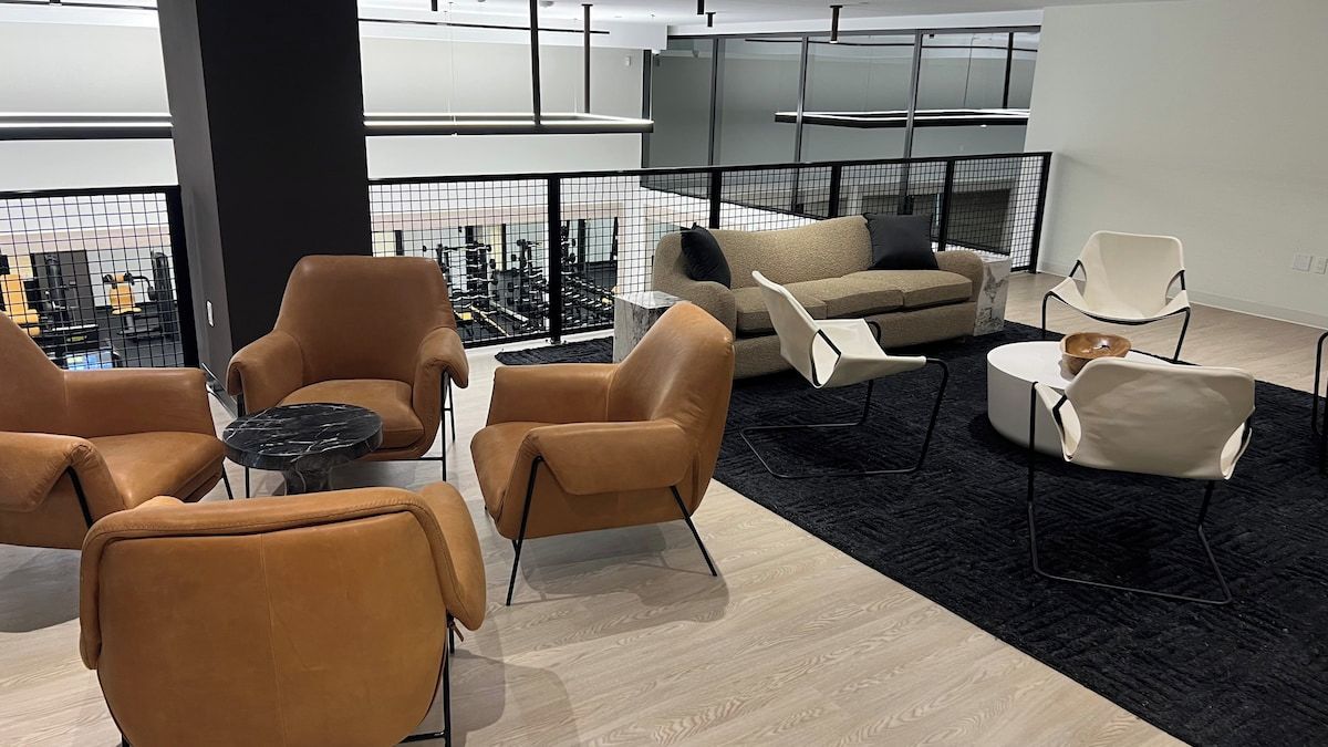 A modern lounge area with leather sofas, a coffee table, and a view of the cityscape.