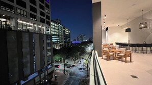 Un bâtiment moderne doté d’un balcon donnant sur une vue panoramique de la ville la nuit.