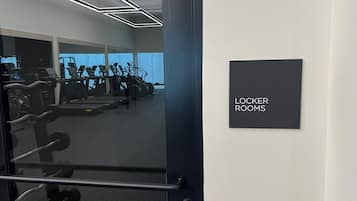 A gym with exercise equipment and a sign indicating 'Locker Rooms'.