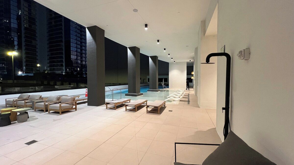 A rooftop lounge area with a pool, lounge chairs, and a modern architectural design.