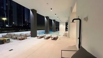 A rooftop lounge area with a pool, lounge chairs, and a modern architectural design.