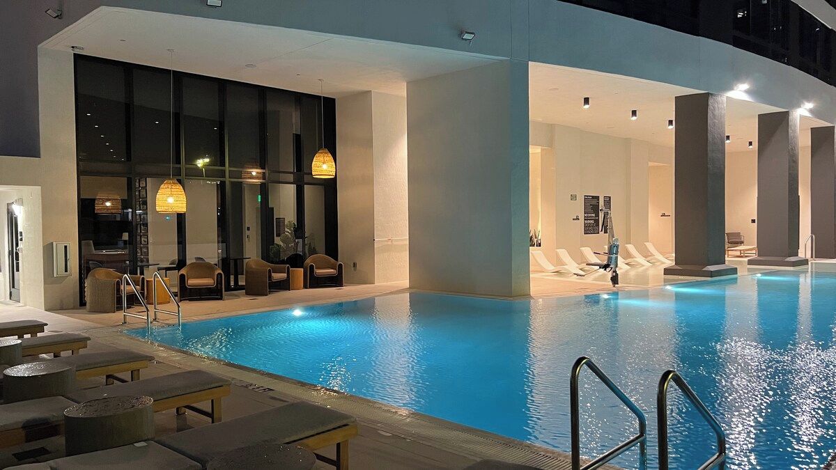 An indoor swimming pool with lounge chairs and a sunbed area.