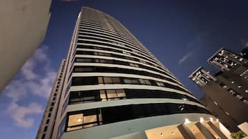 A high-rise building with a curved facade, multiple windows, and a clear sky in the background.