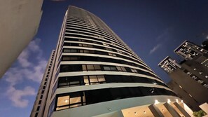 Un edificio de gran altura con fachada curva, múltiples ventanas y cielo despejado al fondo.