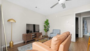 Un soggiorno con divano, televisore e ventilatore a soffitto.