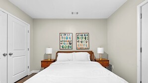 Una camera da letto con un letto grande, due comodini, una testiera in legno e due opere d'arte appese al muro.