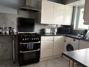Een moderne keuken met een fornuis, oven, magnetron en wasmachine.