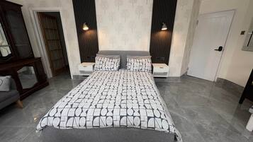 Un dormitorio moderno con una cama grande, dos mesitas de noche, un armario y un espejo.