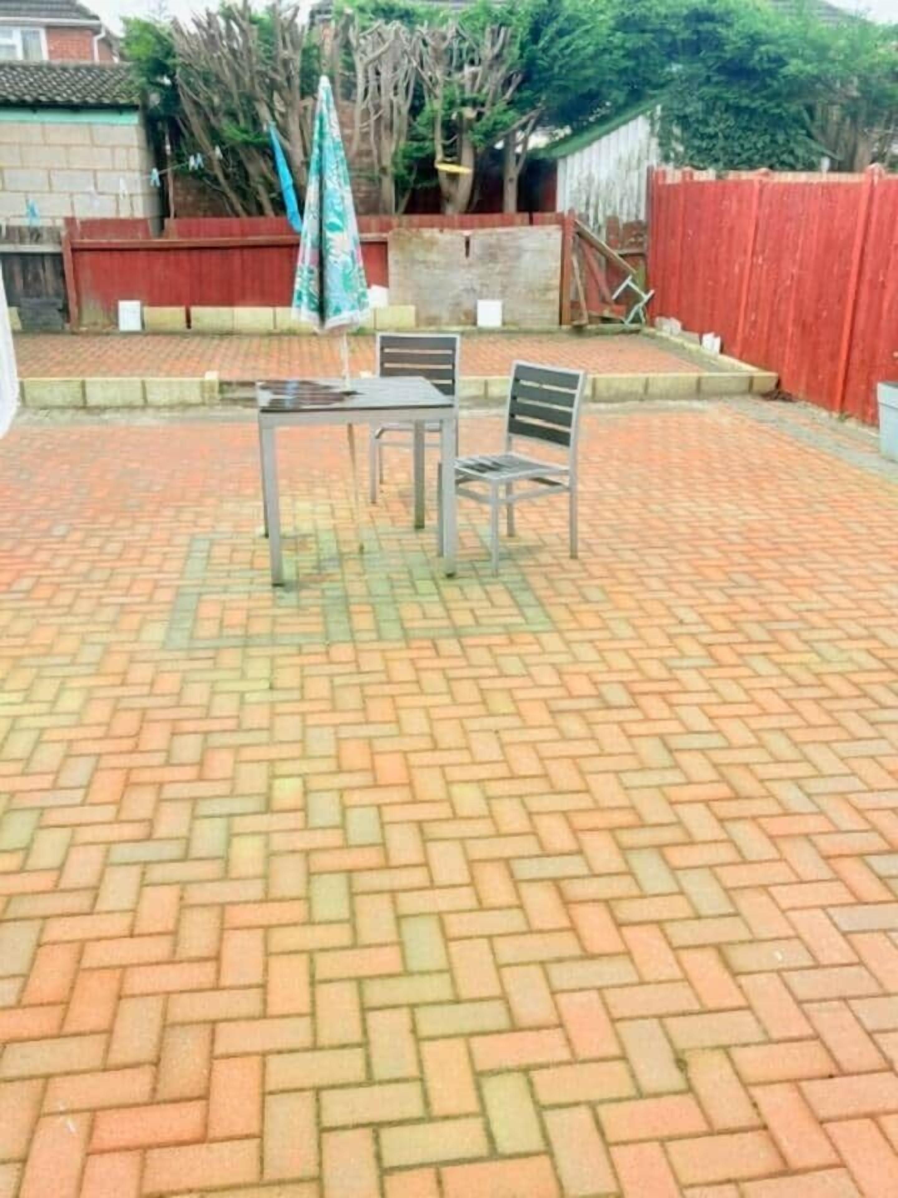Un patio con piso de ladrillo, una mesa y dos sillas.