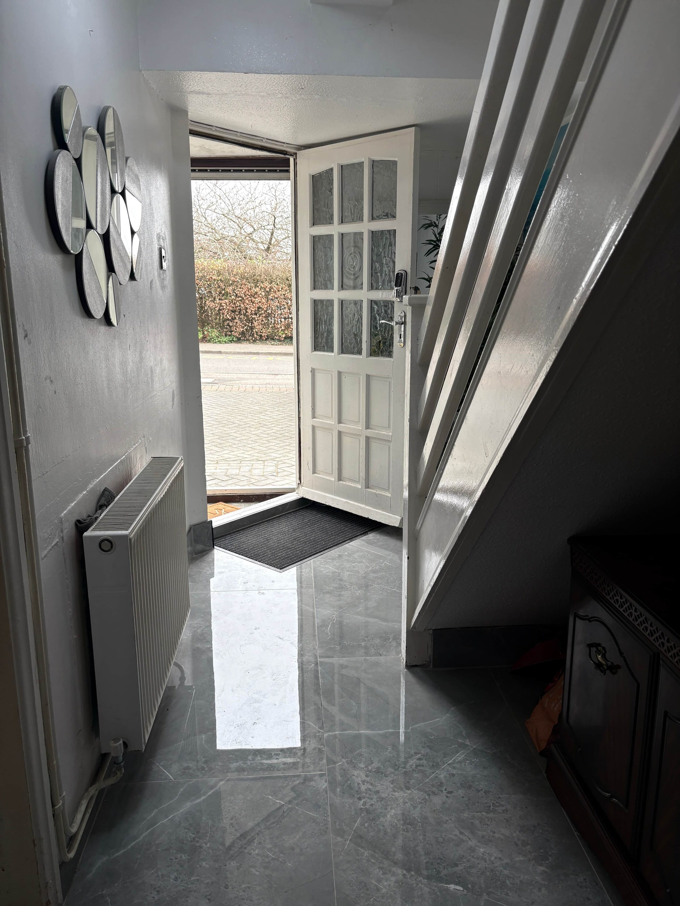 Un couloir avec un radiateur, une porte donnant sur l’extérieur et un escalier.
