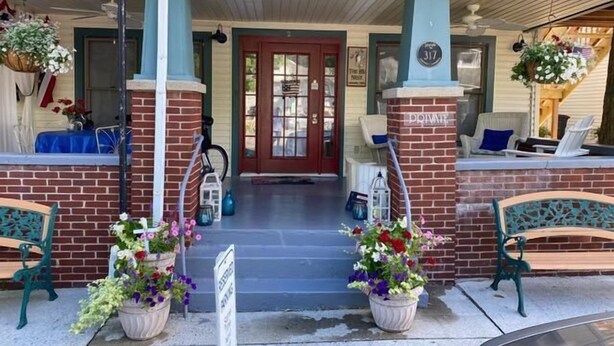 A two-story building with a red door, a balcony with outdoor seating, and potted plants. - 317 Maple Unit 2 in Lakeside (Lakeside)