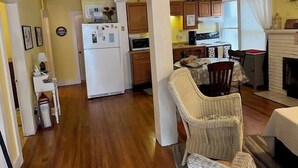 A cozy living room with a fireplace, wooden flooring, and a dining area with a table and chairs. - 317 Maple Unit 2 in Lakeside (Lakeside)