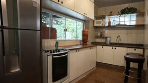 Cucina con frigorifero in acciaio inossidabile, piano cottura e forno a microonde. Una finestra offre vista sul verde circostante.