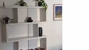 A white shelving unit with plants and books.