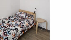A bedroom with a bed, a chair, a mirror, and a painting on the wall.