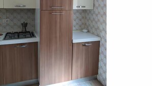 A kitchen with wooden cabinets, a white countertop, and patterned backsplash.