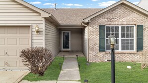 A two-story house with a garage, a front door, and a small front yard with a pathway. - Quiet Stay w Workspace, Fast Wi-Fi & Parking (Fishers)
