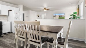 A modern kitchen with white cabinetry, a dark wooden dining table, and two white chairs with black cushions. - Quiet Stay w Workspace, Fast Wi-Fi & Parking (Fishers)