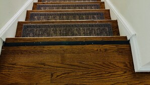 A wooden staircase with carpeted steps leading to an open doorway.
