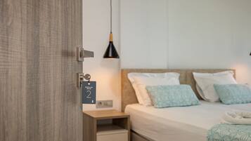 Una camera d'albergo con un letto, un comodino, una lampada e una porta dotata di chiusura a chiave elettronica.