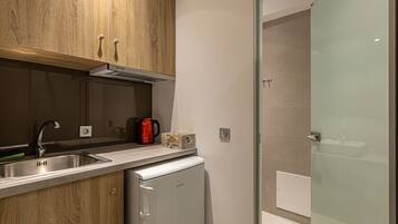 A compact kitchen with wooden cabinets, a stainless steel sink, and a built-in refrigerator.