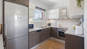 A modern kitchen with stainless steel appliances, wooden cabinets, a dishwasher, and a window with a view. - Euphoria Country House with Jacuzzi and Barbecue (Agios Ioannis)