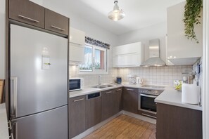 Eine moderne Küche mit Edelstahlgeräten, Holzschränken, einem Geschirrspüler und einem Fenster mit Blick.