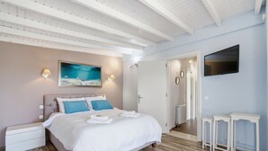 A bedroom with a bed, bedside tables, a TV, and a painting on the wall. - Euphoria Country House with Jacuzzi and Barbecue (Agios Ioannis)