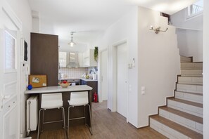 Eine moderne Küche mit weißen Schränken, einer zentralen Kochinsel und einer Treppe zu einer oberen Etage.