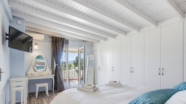 A bedroom with a bed, a desk with a mirror, a television, and a wardrobe. - Euphoria Country House with Jacuzzi and Barbecue (Agios Ioannis)